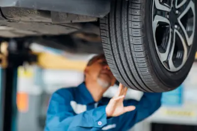 Garagiste contrôlant un pneu adapté aux voitures électriques lors d’un entretien sur véhicule électrique