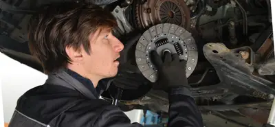 Mécanicien en train de remplacer le disque d’embrayage sous une voiture, intervention sur l’embrayage