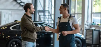 Accueil client en garage automobile - poignée de main entre client et mécanicien en atelier